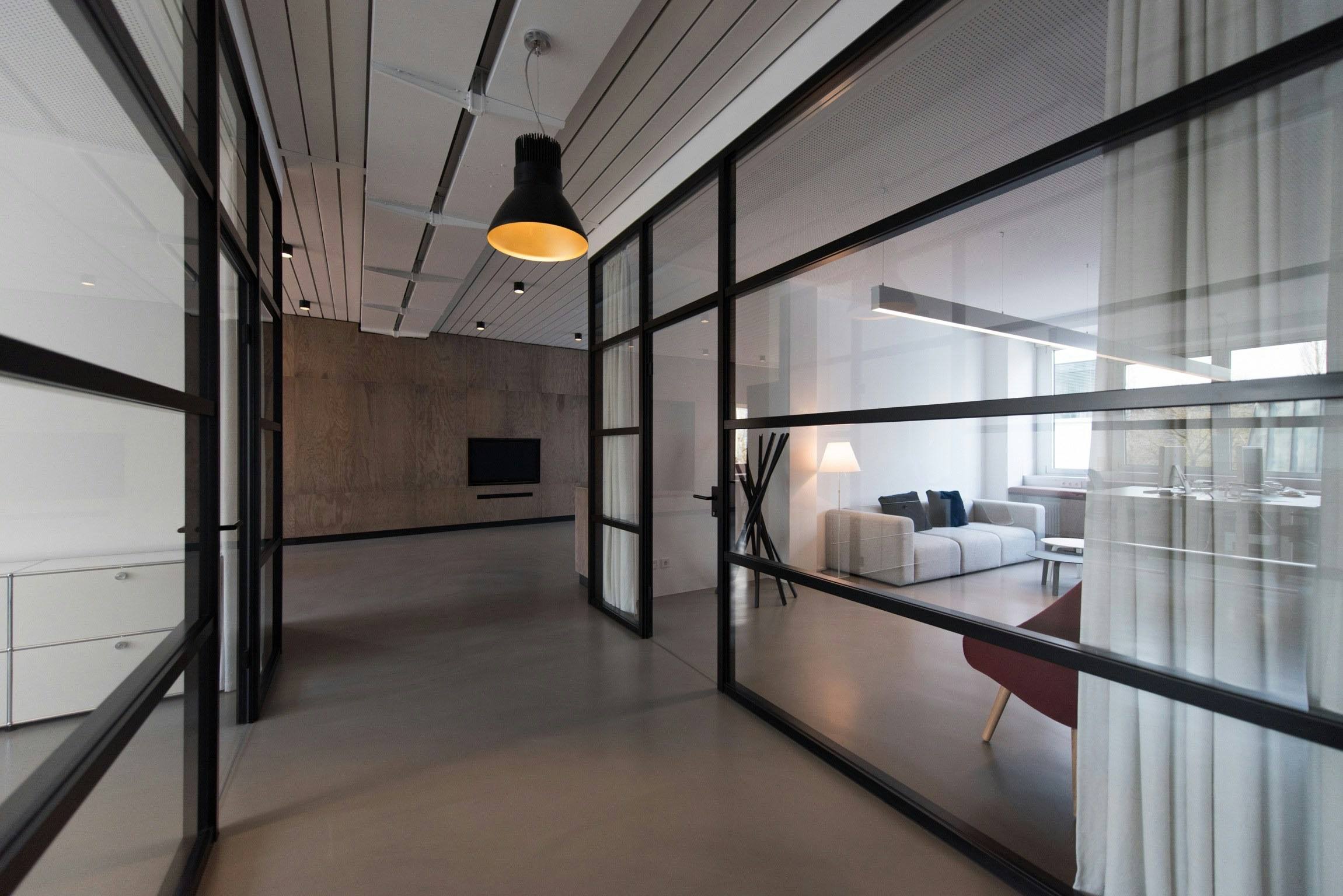 Couloir de bureaux bordé de cloisons vitrées à profils acier noirs